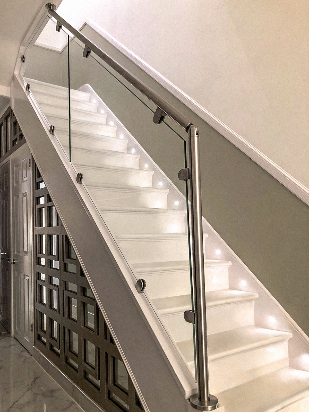 Indoor White wooden staircase complemented with glass balustrade & steel banister