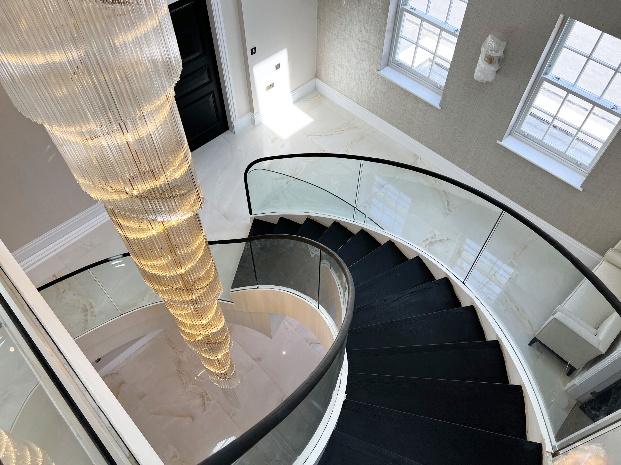 Helical staircase complemented with Curved glass balustrades, black oak steps & wooden handrail.