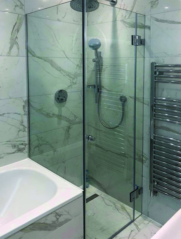 Glass shower enclosure with bathtub attached to it