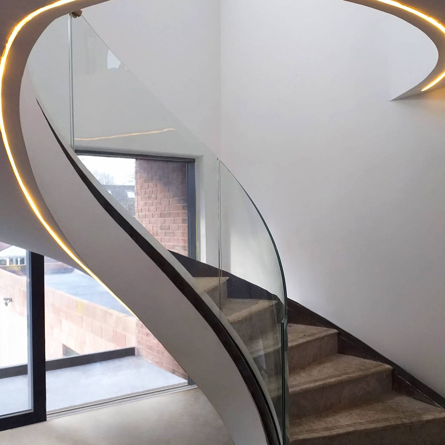 Helical glass staircase with curved balustrade
