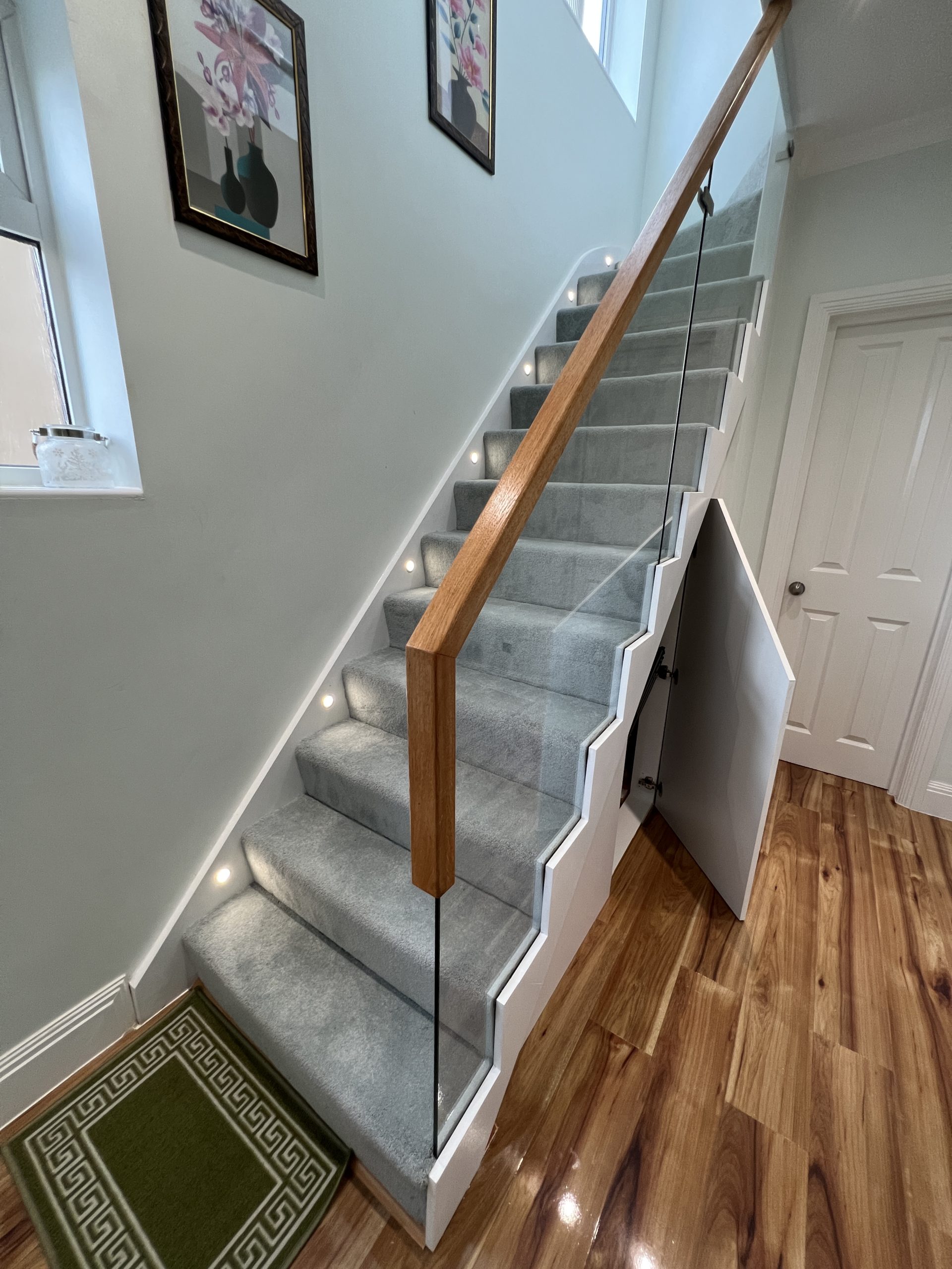 Wooden staircase with grey carpet and wooden handrail