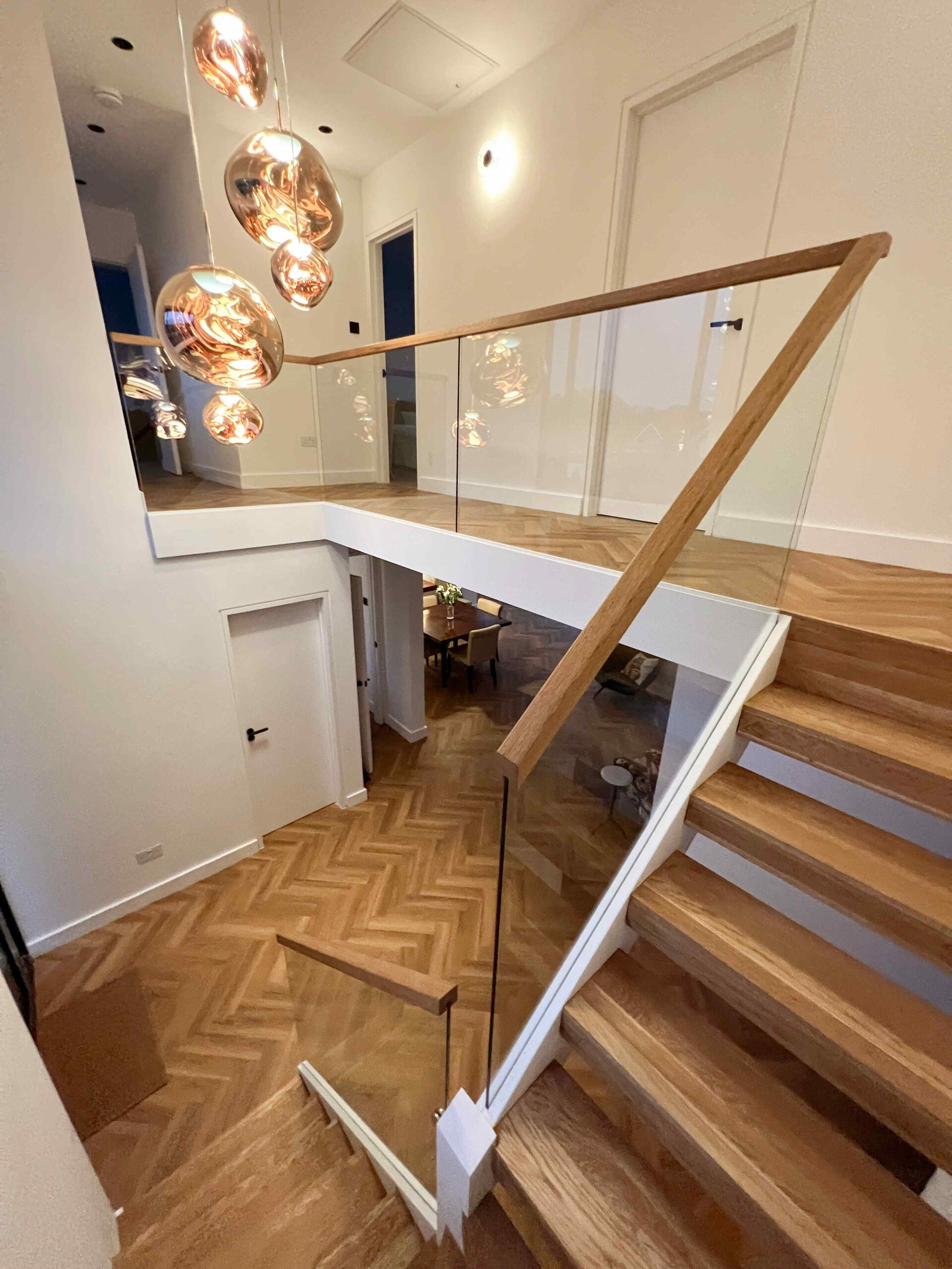 Floating staircase with glass balustrade, oak handrail on top