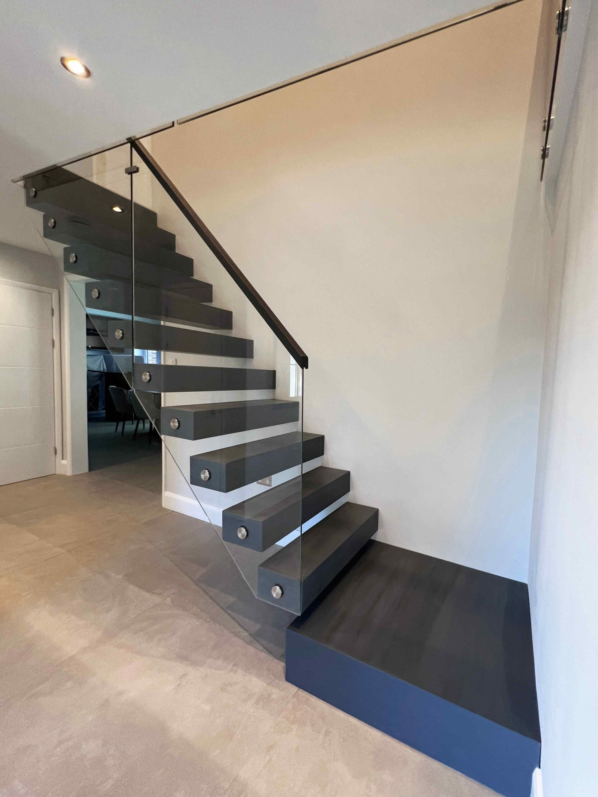 Floating staircase complemented with glass balustrade and black oak stair treads.